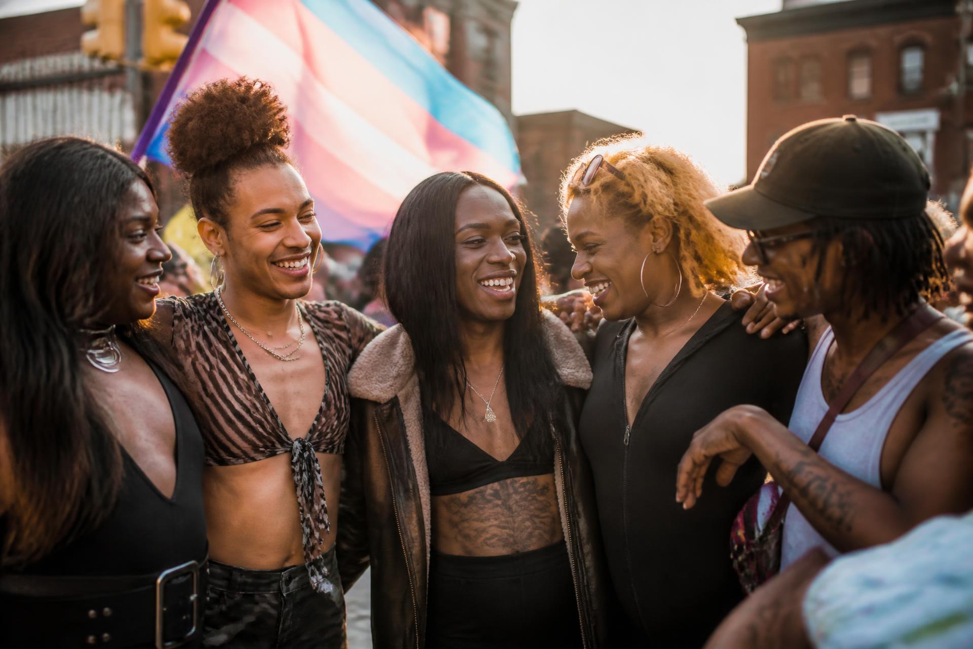 LGBTQ+ community members embracing and laughing together at golden hour